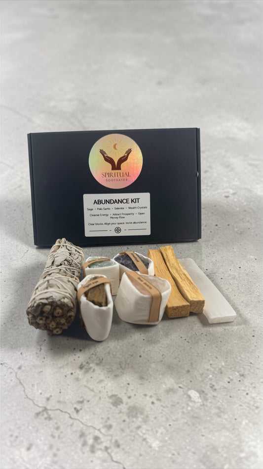 Abundance kit with sage, wooden tools, and packaging on a gray surface