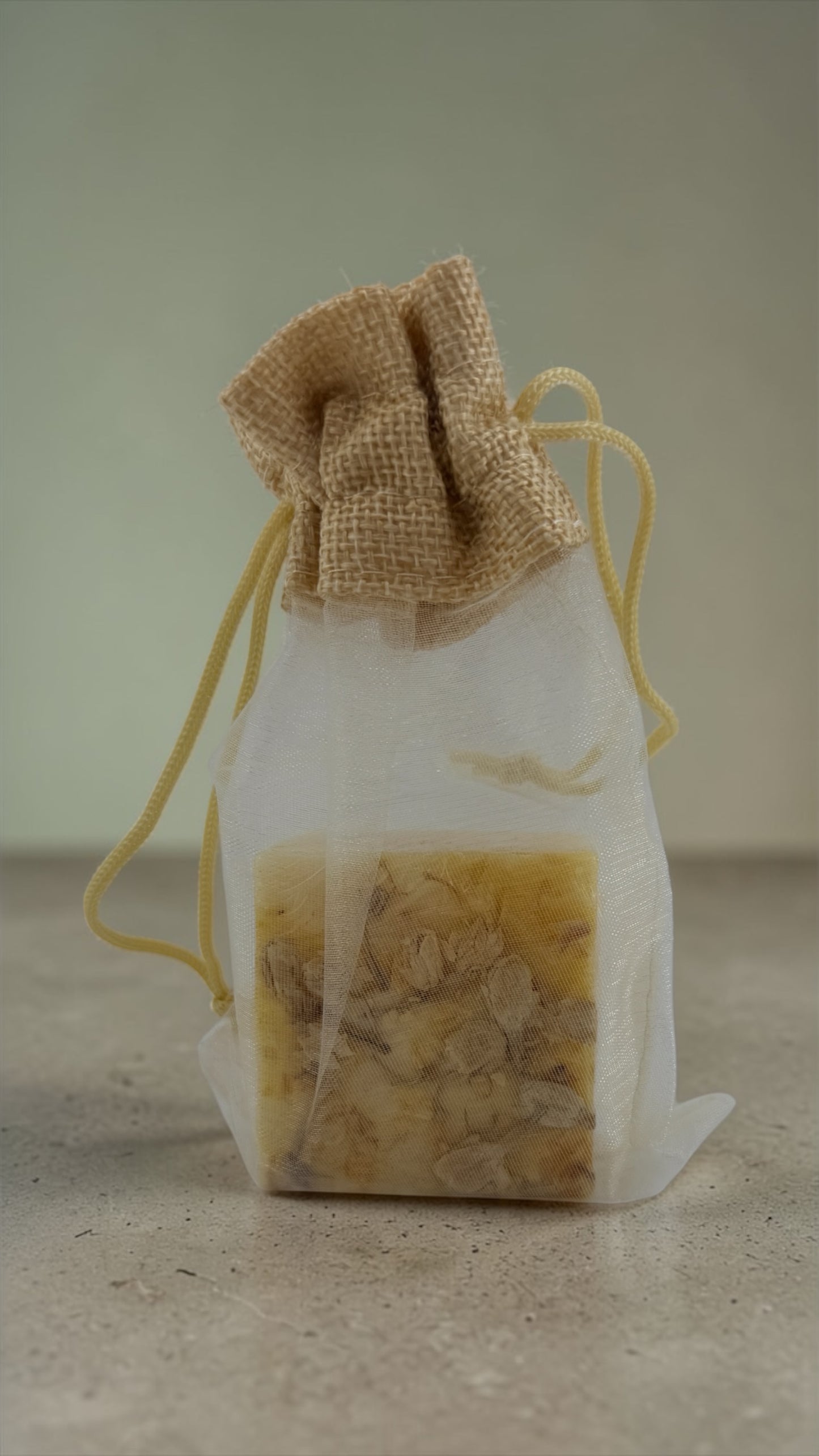 Bar of soap in a drawstring bag on a neutral background