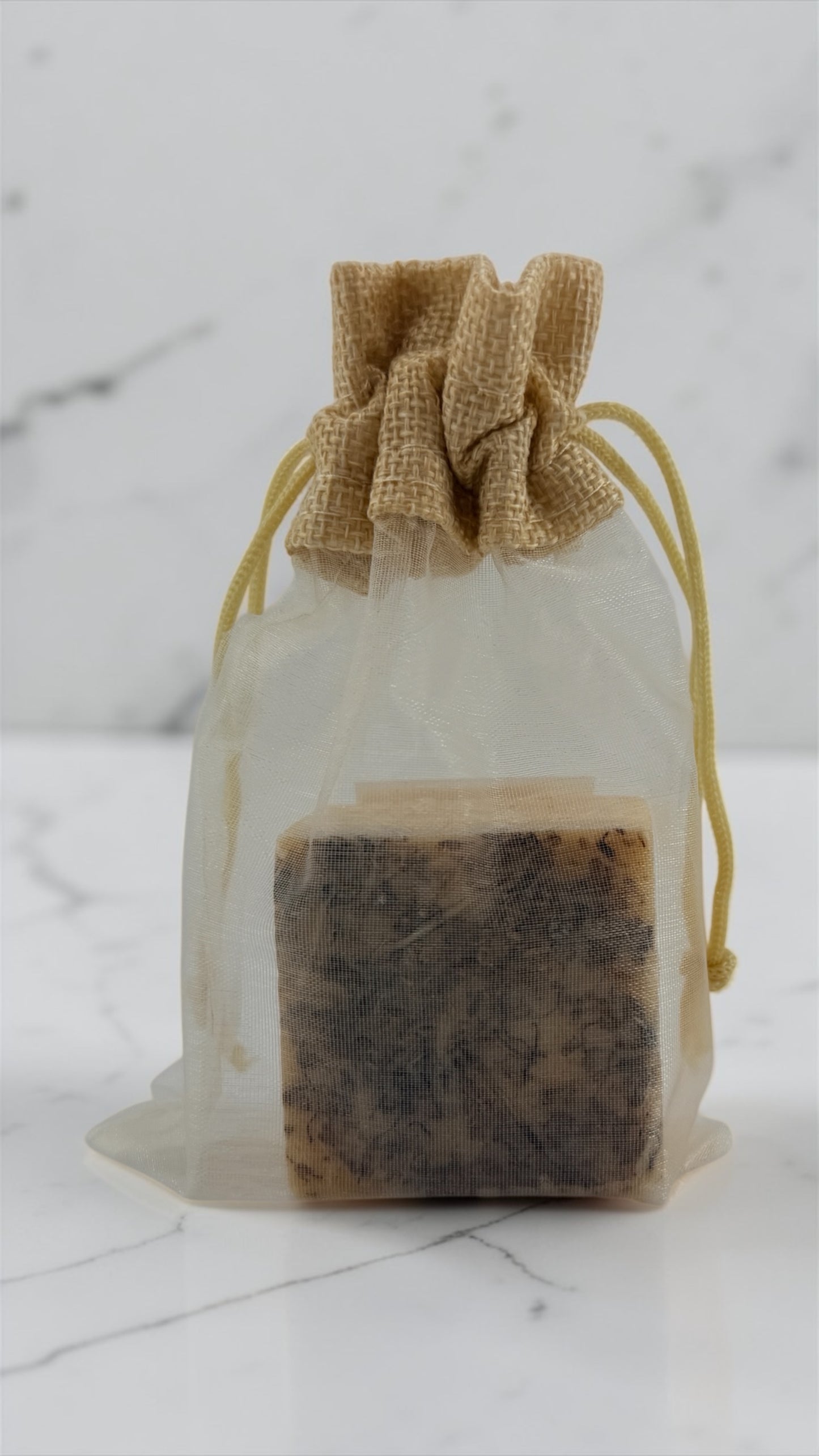 Bar of soap in a clear drawstring bag on a marble surface