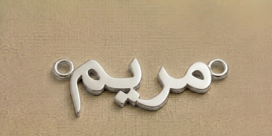 Silver jewelry piece with Arabic script on a beige background