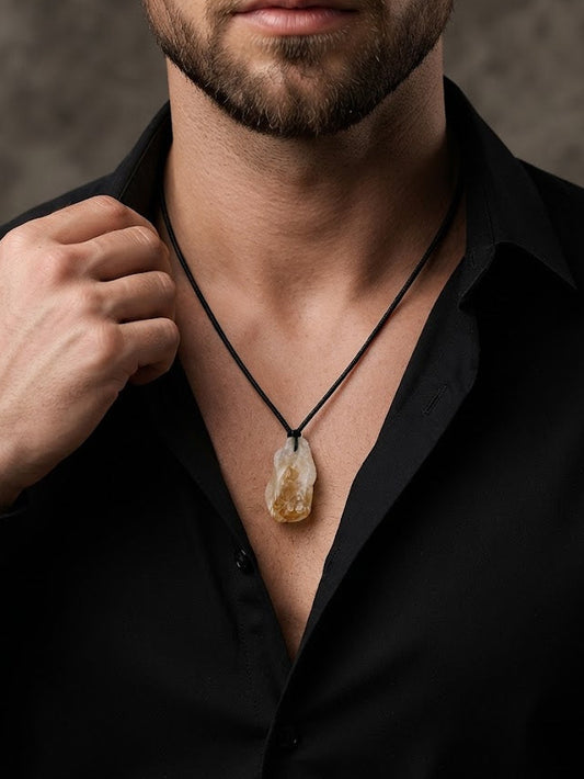 A close-up of a man wearing a black cord necklace with a polished, irregular-shaped natural stone pendant, styled with a black button-down shirt.