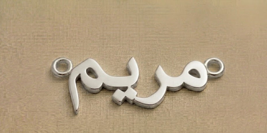 Silver jewelry piece with Arabic script on a beige background