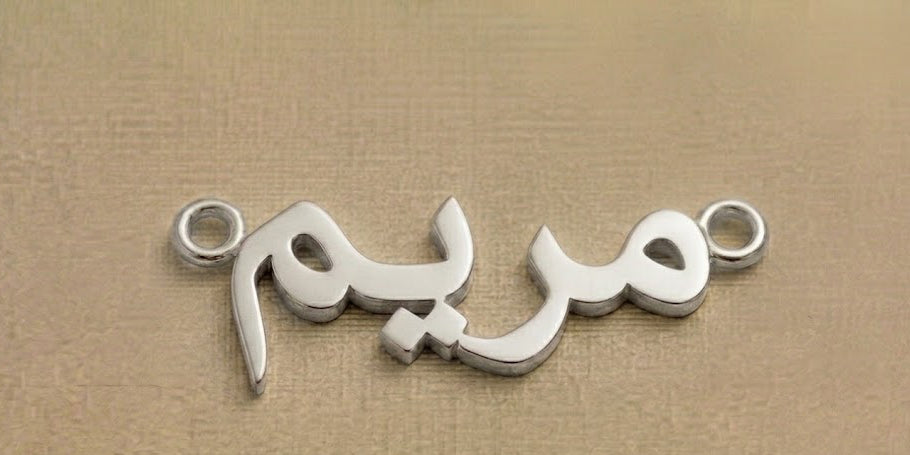 Silver jewelry piece with Arabic script on a beige background