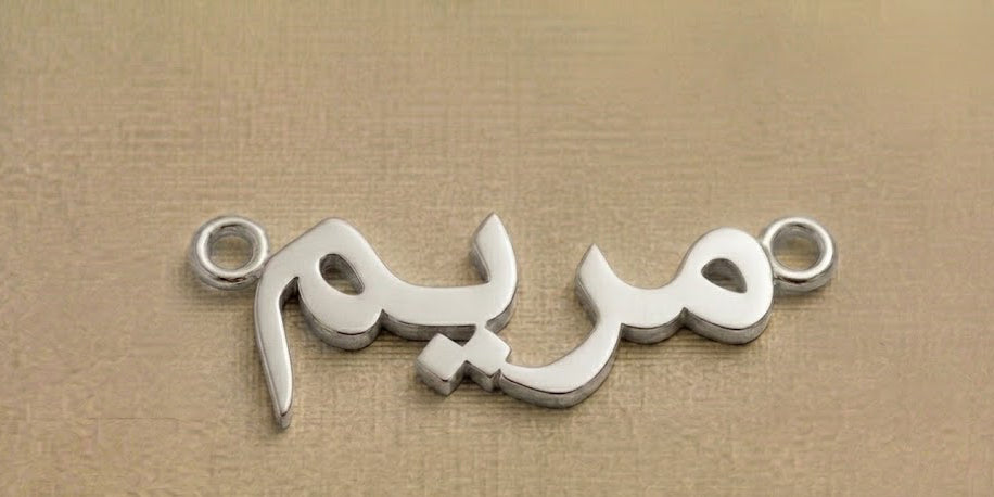 Silver jewelry piece with Arabic script on a beige background