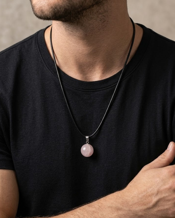 Man wearing a black t-shirt with a necklace featuring a pink pendant.