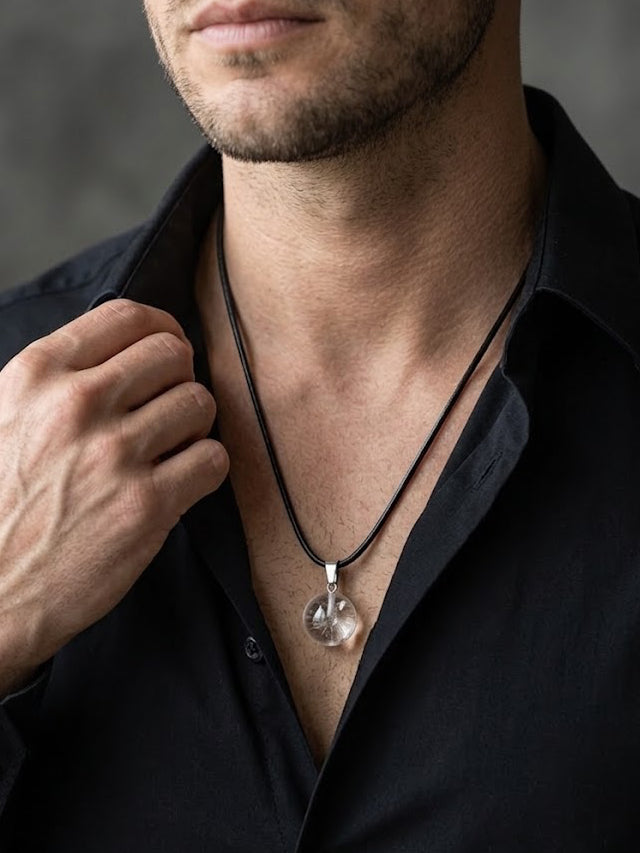 Man wearing a black shirt with a necklace against a gray background