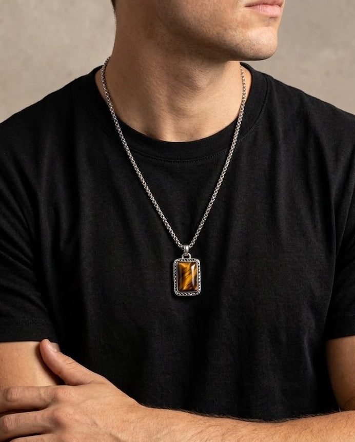 Man wearing a black t-shirt with a silver necklace featuring a rectangular pendant.