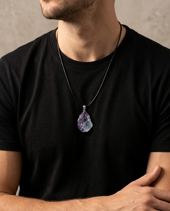 Man wearing a black t-shirt with a necklace featuring a purple pendant.