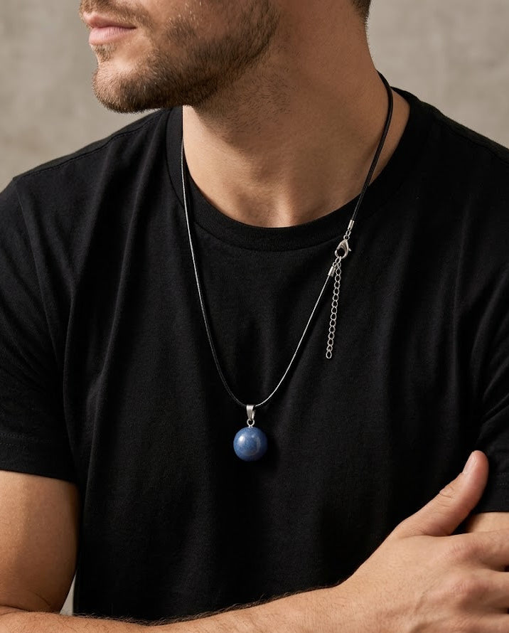 Man wearing a black t-shirt with a necklace featuring a blue pendant.