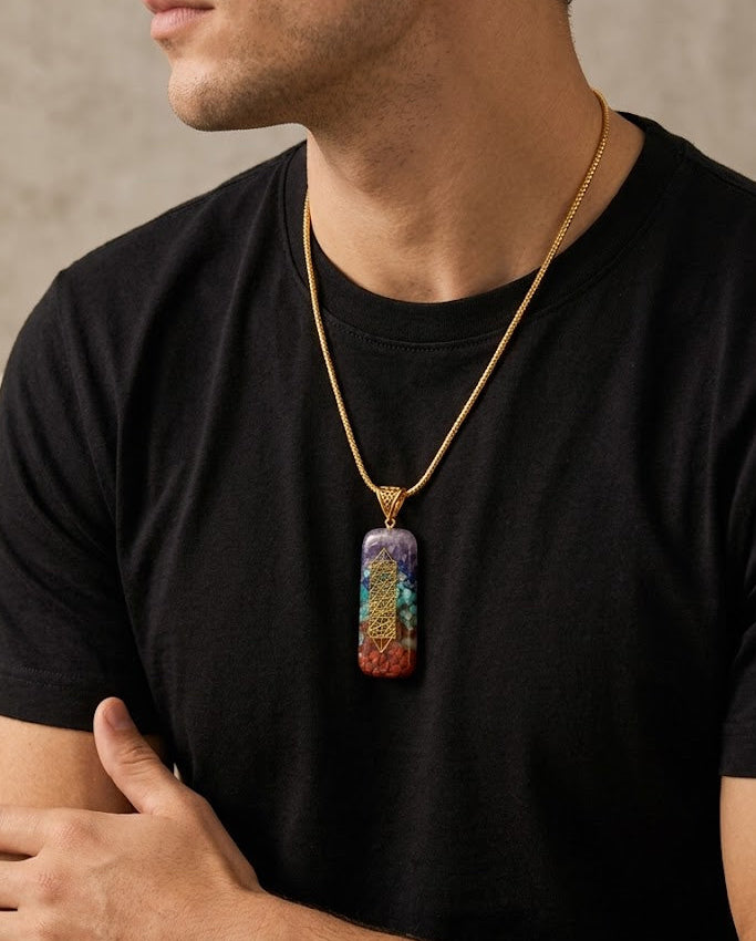 Man wearing a black t-shirt with a colorful pendant necklace against a neutral background