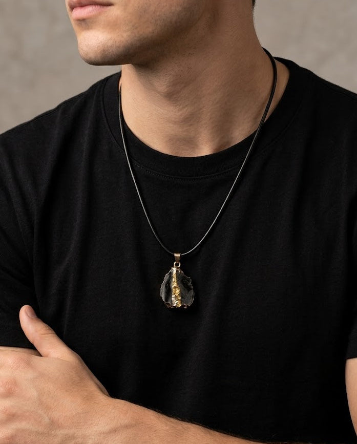 Man wearing a black t-shirt with a necklace featuring a pendant.