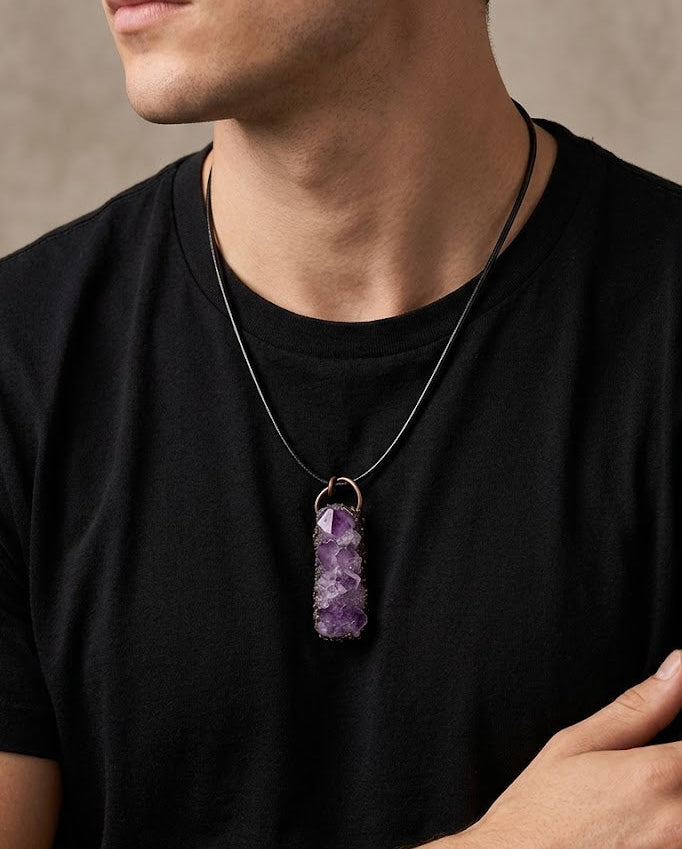 Man wearing a black t-shirt with a purple amethyst pendant necklace.