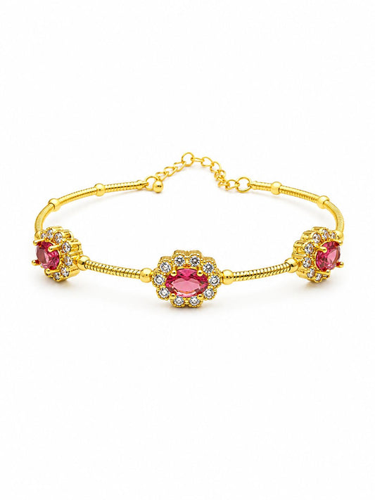 A gold-toned bracelet featuring three oval pink gemstone clusters, each surrounded by small clear stones, displayed on a clean white background.