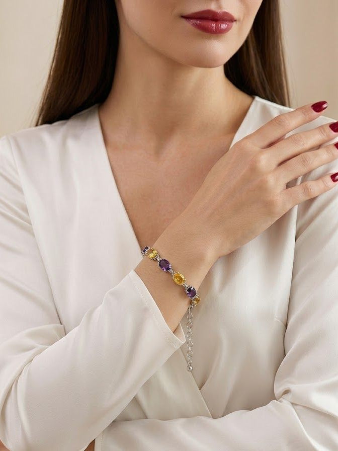 A close-up of a woman wearing a delicate beaded bracelet on her wrist. The bracelet features small purple and yellow beads with a silver-toned chain extender.
