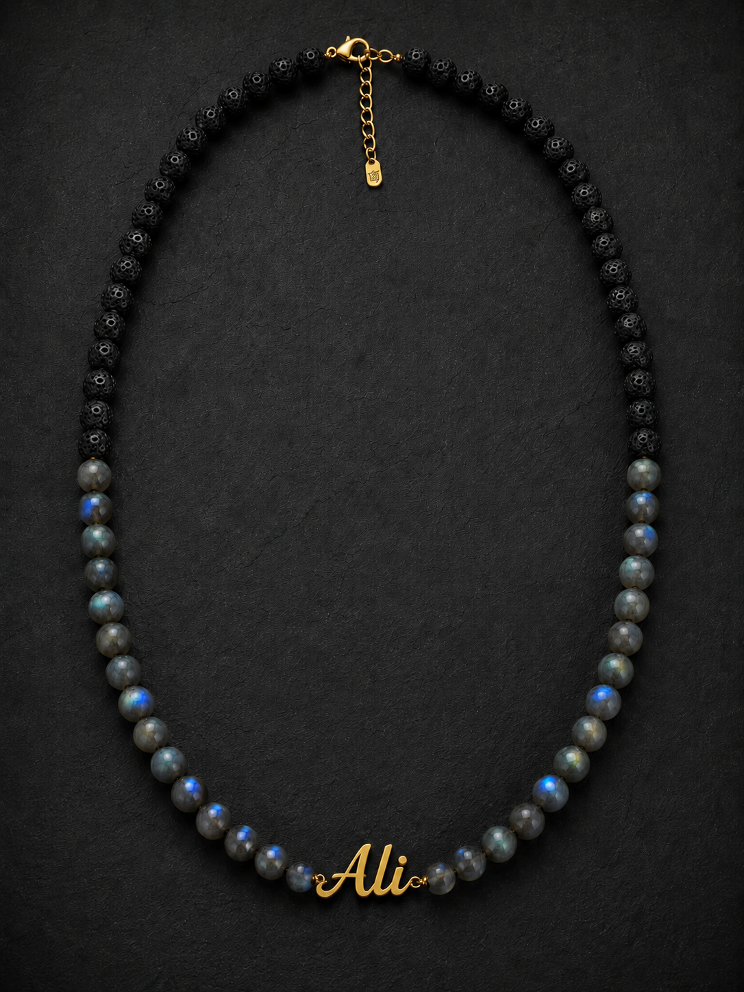 Necklace with black and gray beads and 'Ali' engraving on a dark background