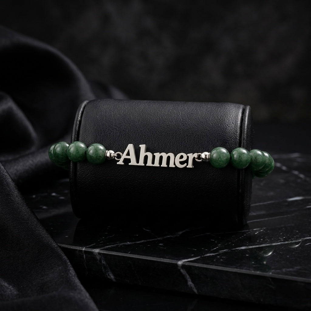Bracelet with green beads and a nameplate on a black leather case with a dark background