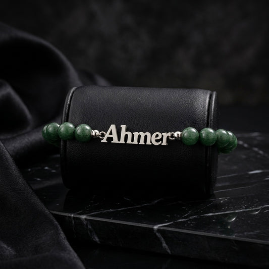 Bracelet with green beads and a nameplate on a black leather case with a dark background