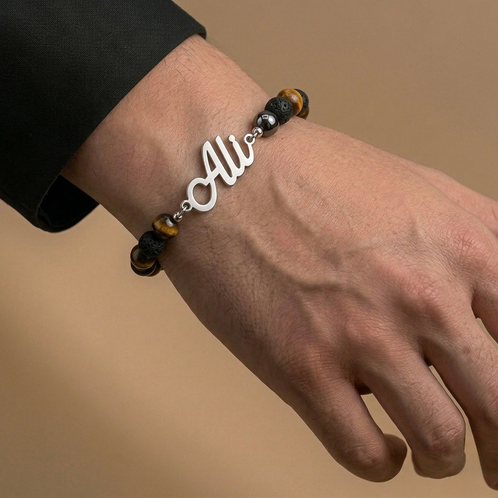 Bracelet with 'Ali' charm on a wrist against a beige background