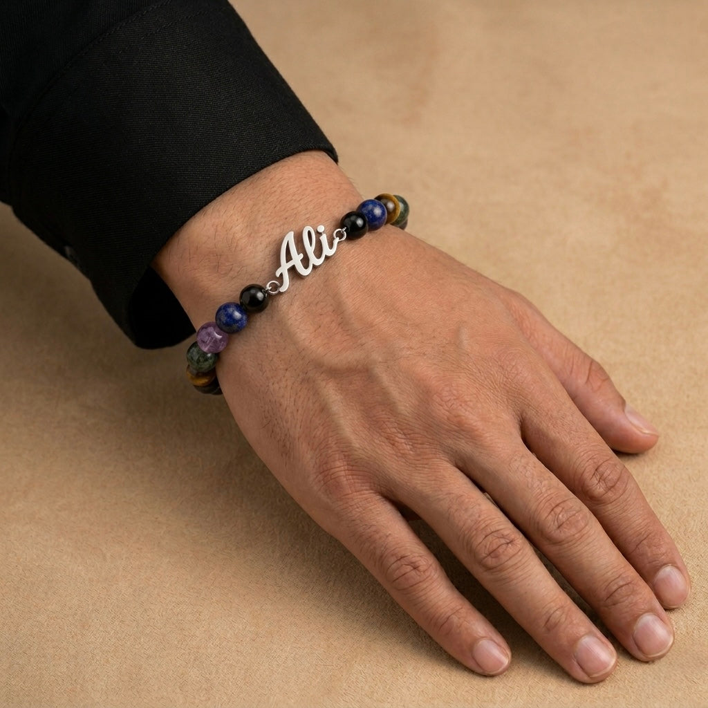 Hand wearing a bracelet with a 'Ali' charm on a beige background