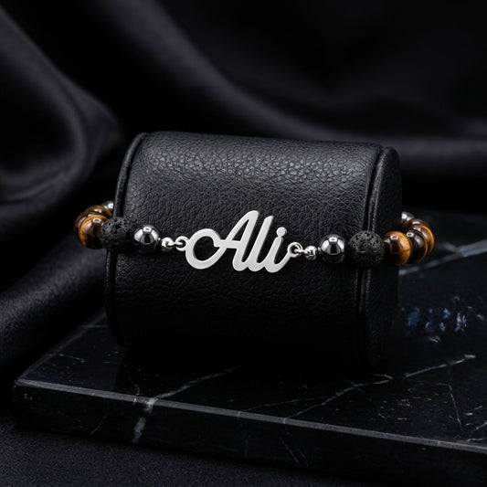 Bracelet with 'Ali' charm on a black leather case against a dark background