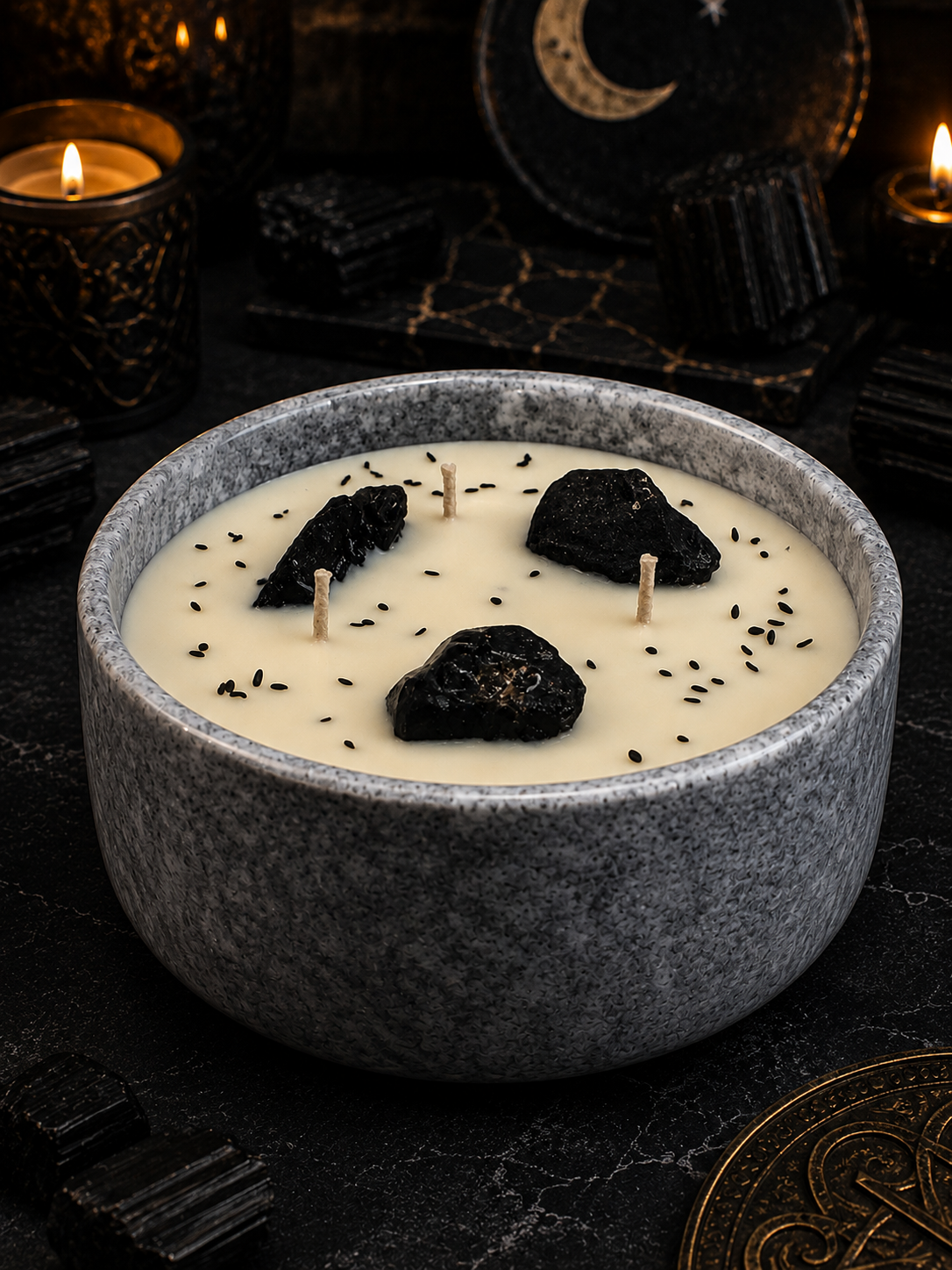 Candle in a gray bowl with black stones and wicks on a dark background