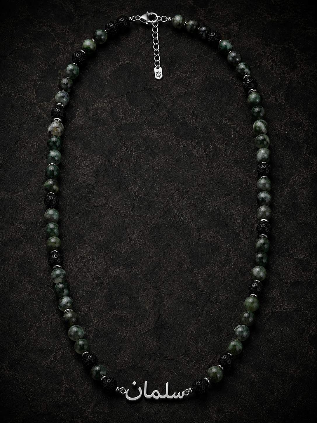 Necklace with black and green beads on a dark background