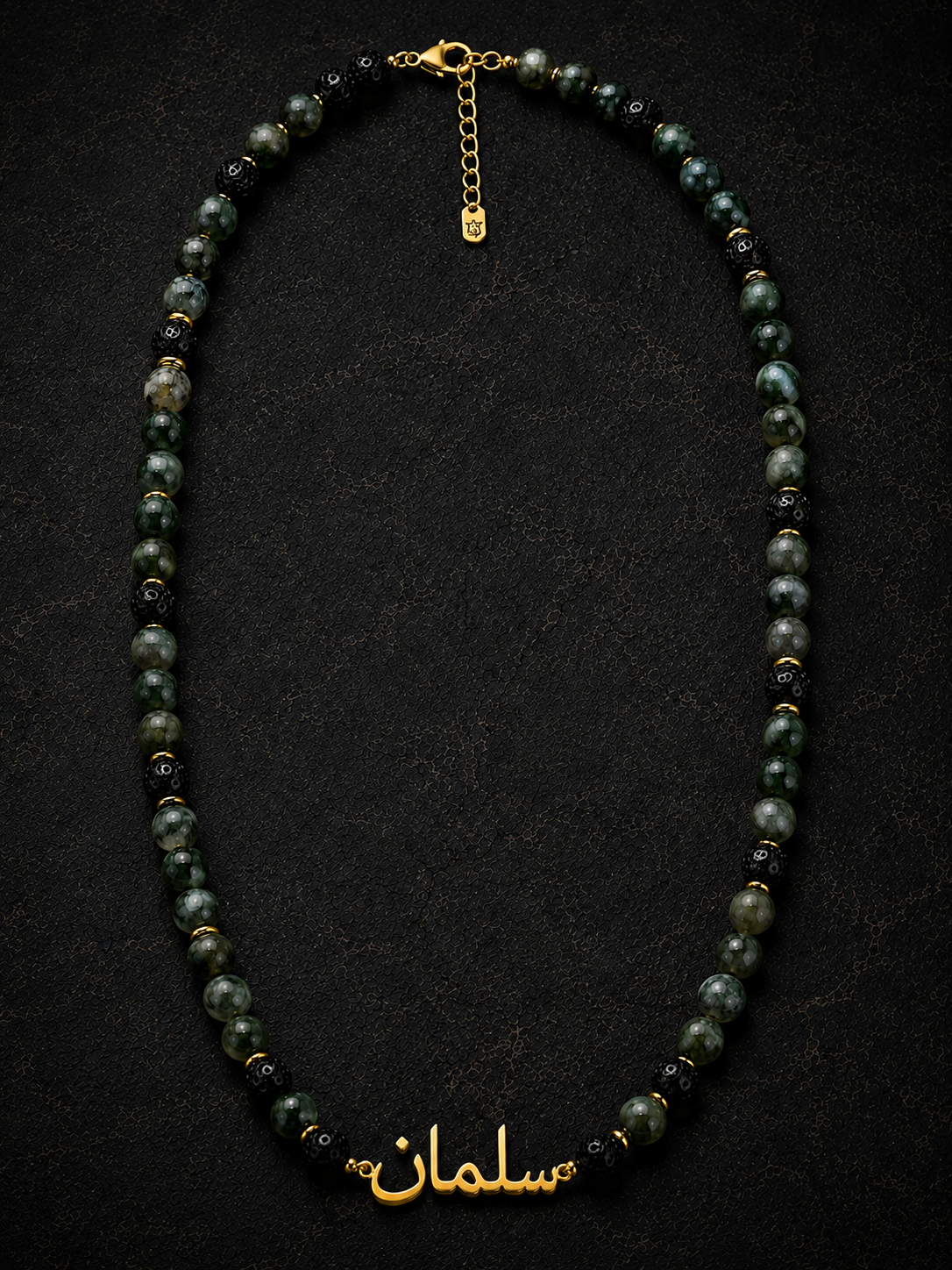 Necklace with black beads and gold chain on a dark background