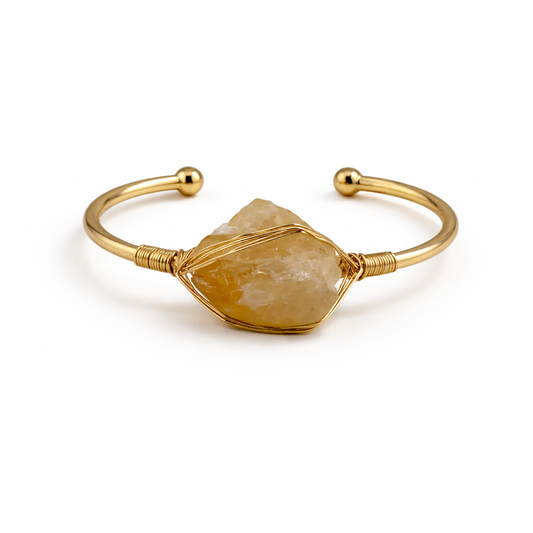 Gold bracelet with a large stone on a white background