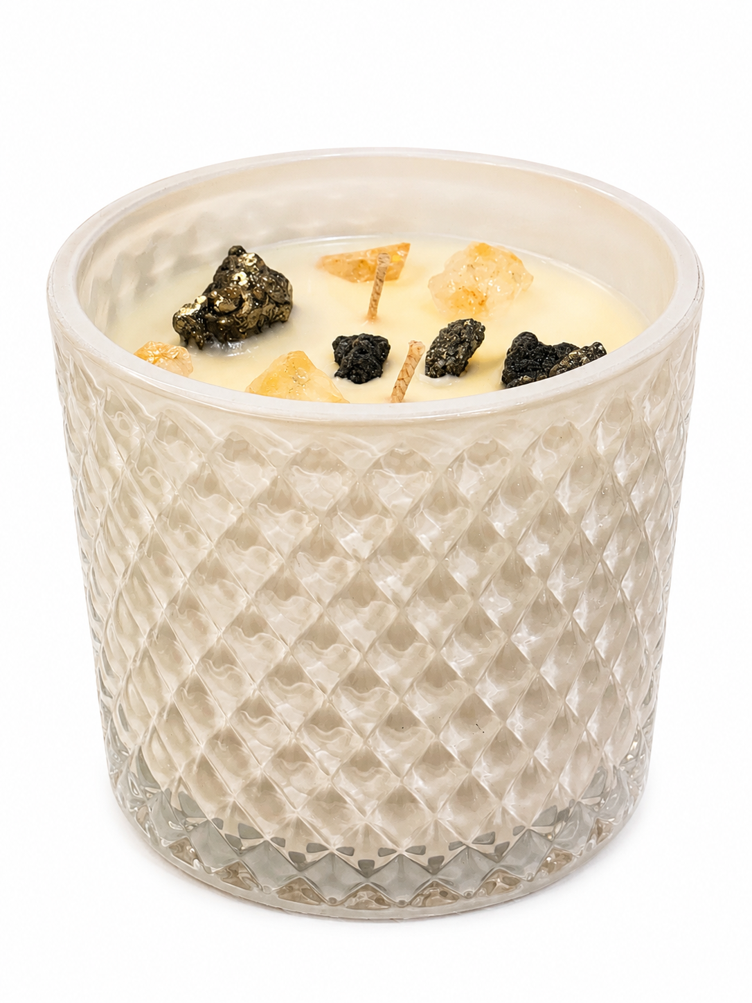 Candle in a textured glass container with decorative elements on a white background