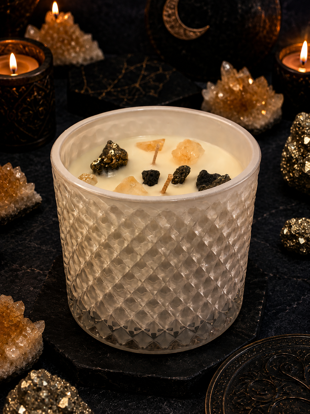 Candle in a textured glass holder with decorative stones on a dark background
