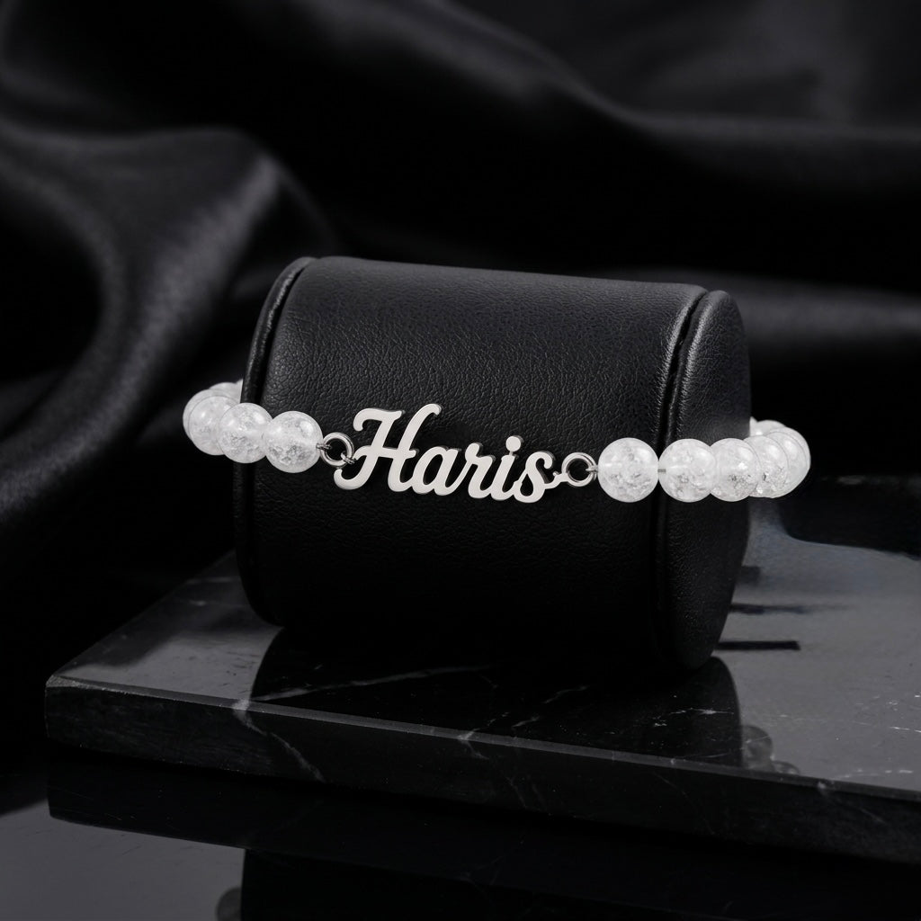 Pearl bracelet with 'Haris' on a black box against a dark background