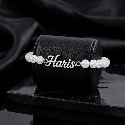 Pearl bracelet with 'Haris' on a black box against a dark background