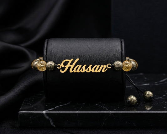 Black leather case with gold beads and 'Hassan' engraving on a dark background