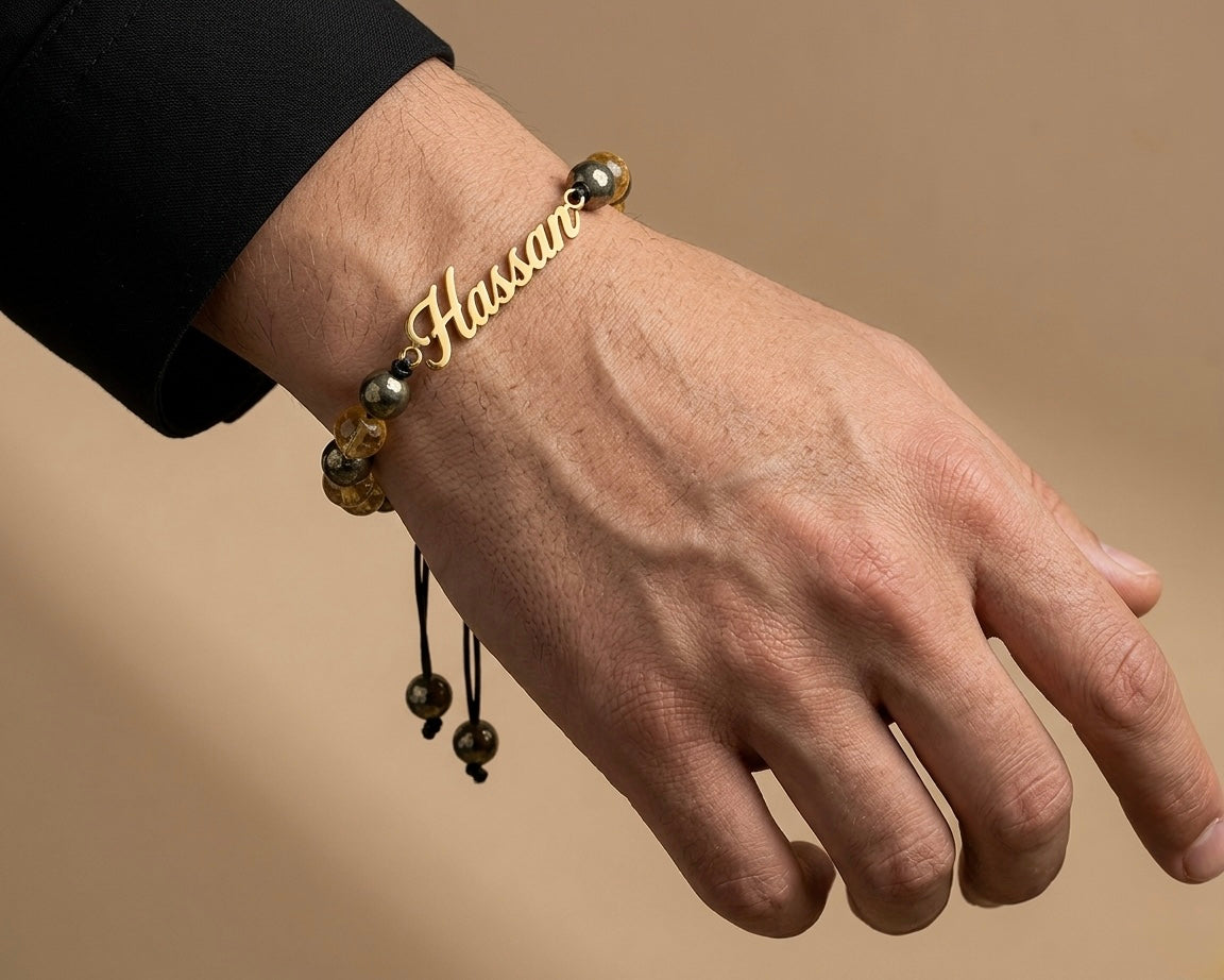 Hand wearing a gold bracelet with beads on a beige background