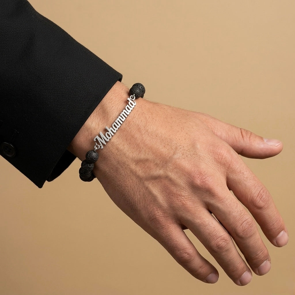 Hand wearing a bracelet with 'Mohammad' engraved on a beige background